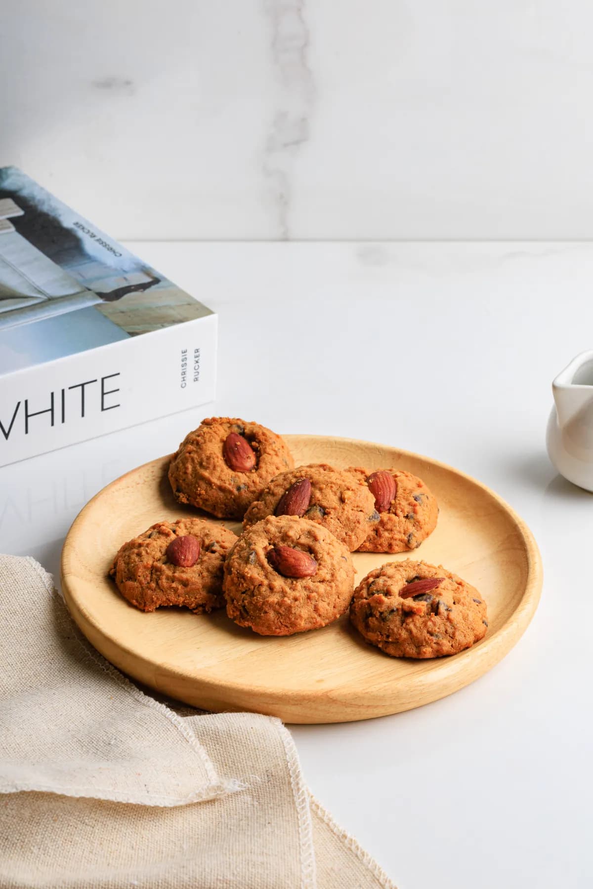 Almond cookies on a wooden plate with linen and marble background.