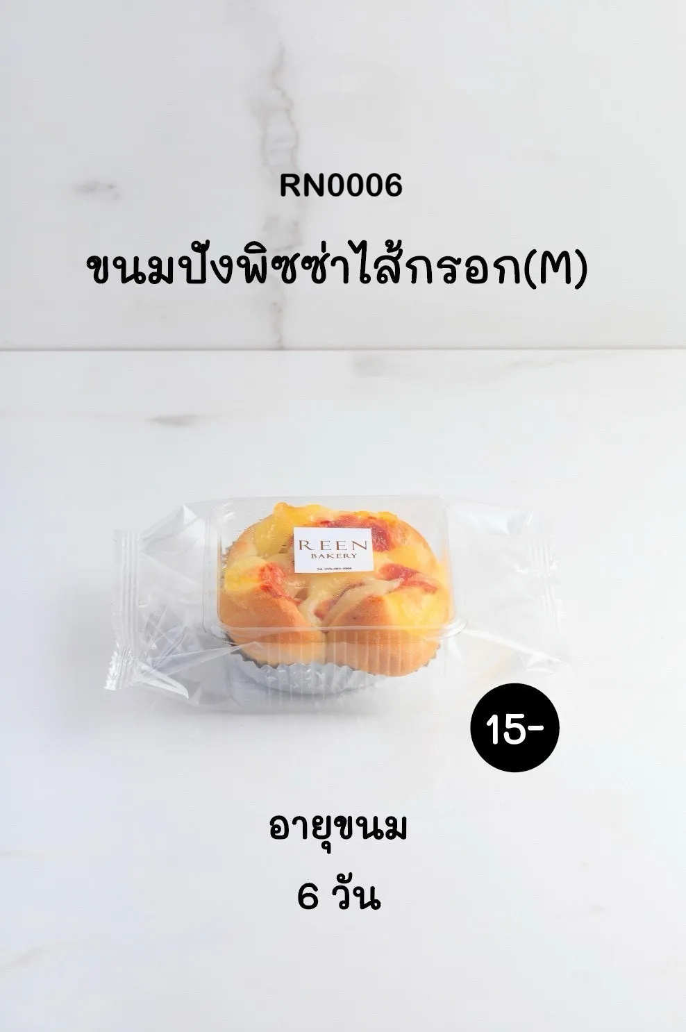 ขนมปังพิซซ่าไส้กรอกขนาดกลางหนึ่งชิ้นในแพ็กเกจพลาสติกใส มองเห็นหน้าชีสสีเหลืองทอง ไส้กรอก และซอสสีแดง วางอยู่บนถ้วยฟอยล์สีเงินบนพื้นผิวสีขาว