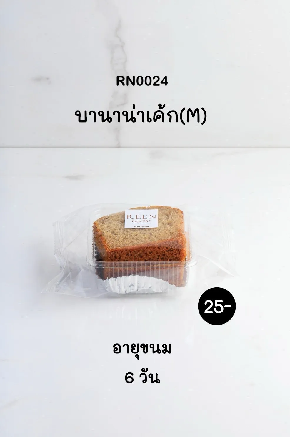 บานาน่าเค้ก (M) หนึ่งชิ้นในกล่องพลาสติกใสพร้อมป้ายโลโก้ REEN BAKERY วางอยู่บนพื้นผิวหินอ่อนสีขาว