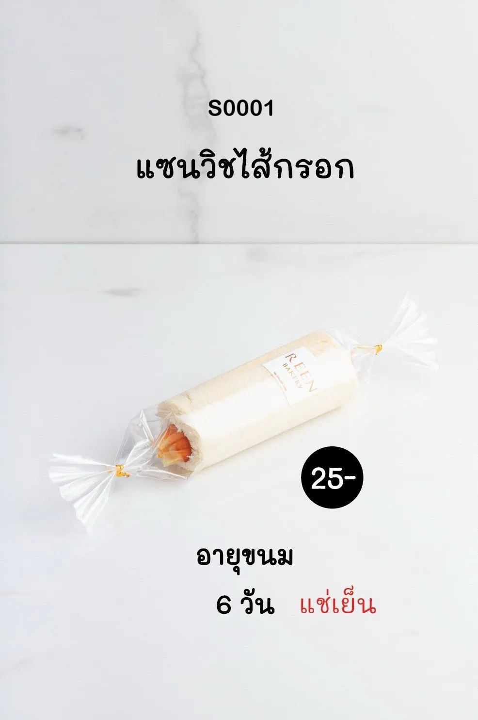 แซนวิชไส้กรอกแบบโรล ห่อด้วยพลาสติกใส ผูกหัวท้าย มีฉลาก REEN BAKERY เห็นไส้กรอกสีส้มอยู่ด้านใน วางอยู่บนพื้นผิวหินอ่อนสีขาว